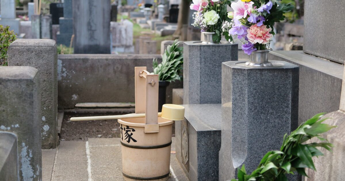 墓参り用の桶と墓石と供花
