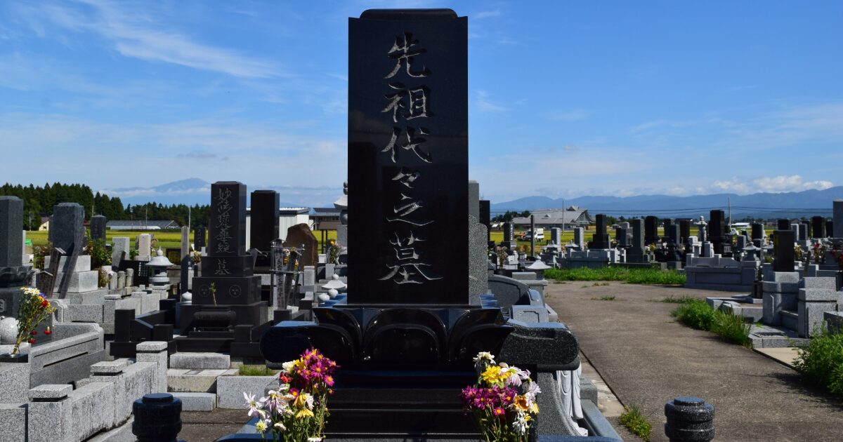 日本の霊園に建つ黒い墓石と青空